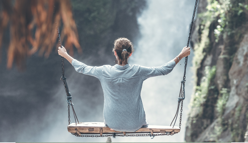 Mastering Mindfulness picture of a girl sitting on a swing in front of a huge waterfall
